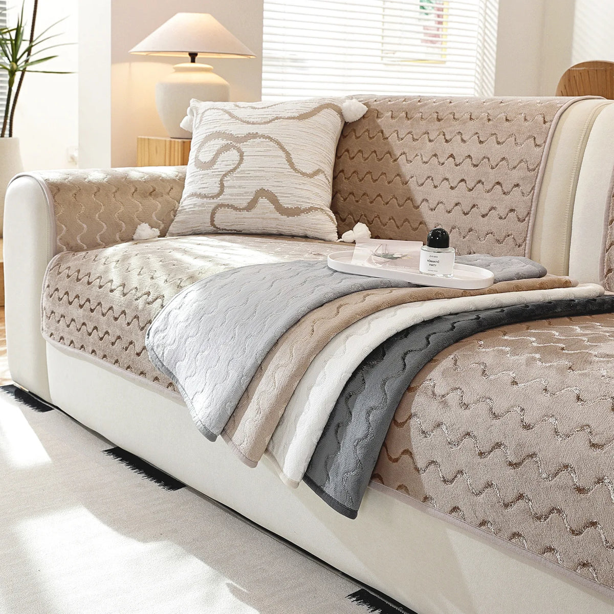 Un canapé confortable garni de coussins et de couvertures dans des tons neutres, offrant une ambiance cocooning et relaxante dans une pièce lumineuse.