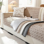 Un canapé confortable garni de coussins et de couvertures dans des tons neutres, offrant une ambiance cocooning et relaxante dans une pièce lumineuse.