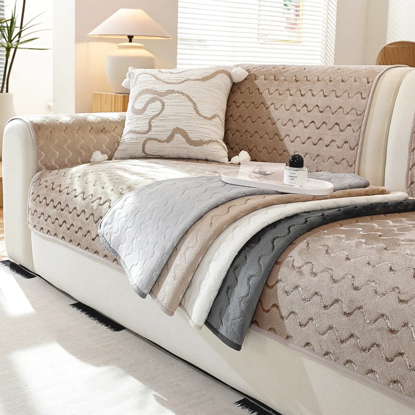 Un canapé confortable garni de coussins et de couvertures dans des tons neutres, offrant une ambiance cocooning et relaxante dans une pièce lumineuse.