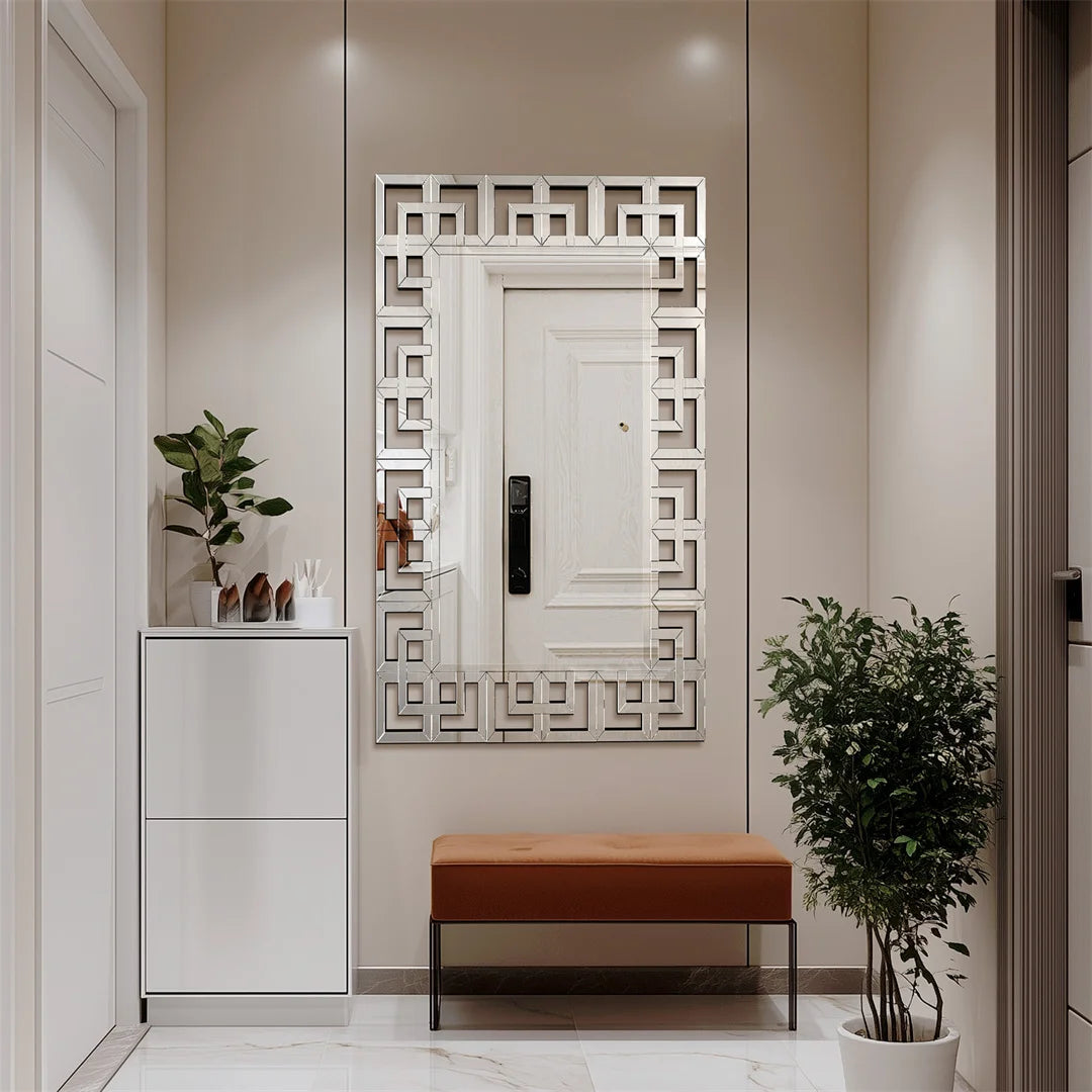 Miroir décoratif moderne avec un cadre en métal de style géométrique, un banc en cuir brun et une plante verte dans le hall d'entrée d'un appartement élégant.