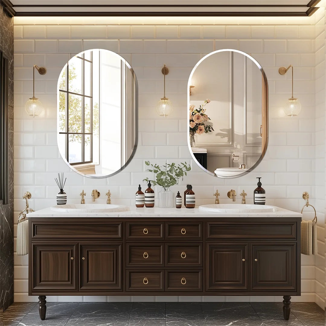 Magnifique salle de bain avec deux grands miroirs ovales encadrés de luminaires dorés, un meuble-lavabo en bois foncé avec de nombreux tiroirs et portes, et une déco végétale apportant une touche naturelle.