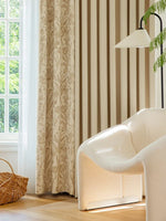 Salon élégant avec rideau crème à motifs floraux, fauteuil bouclette et lumière naturelle