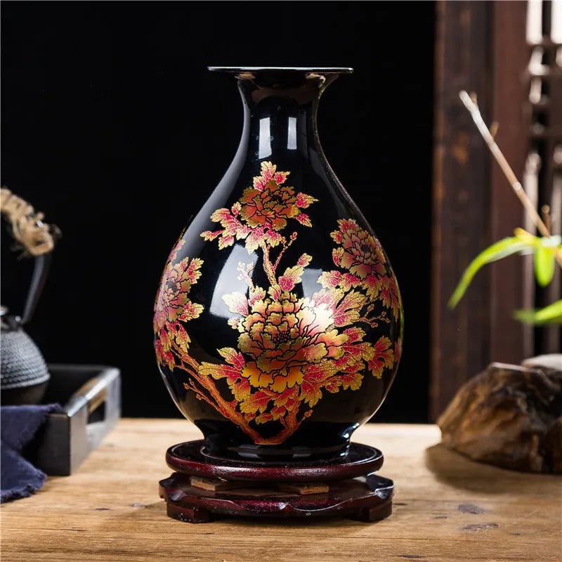 Vase noir orné de fleurs dorées et rouges sur un support en bois, créant une belle décoration d'intérieur rustique.