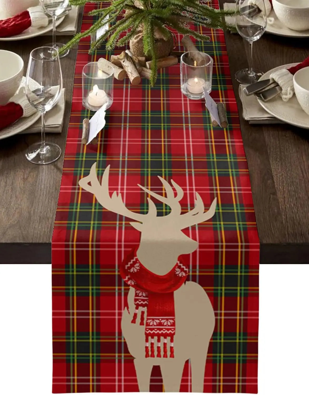 Une élégante décoration de table festive, avec une nappe à carreaux rouges et verts, des bougies, des branches de sapin et une silhouette de cerf en papier blanc, créant une ambiance chaleureuse et conviviale pour un repas de Noël.