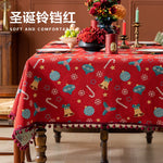 Une magnifique nappe de table rouge ornée de motifs de Noël colorés, comme des boules, des cloches et des flocons de neige, créant une ambiance festive et chaleureuse pour les fêtes.