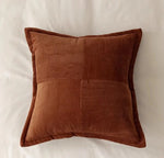 Un coussin marron en velours côtelé, avec des motifs texturés, offrant une touche chaleureuse et élégante à tout espace.