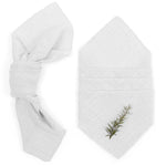 Un ensemble de serviettes de bain blanches luxueuses, avec une décoration naturelle subtile d'une brindille de romarin.