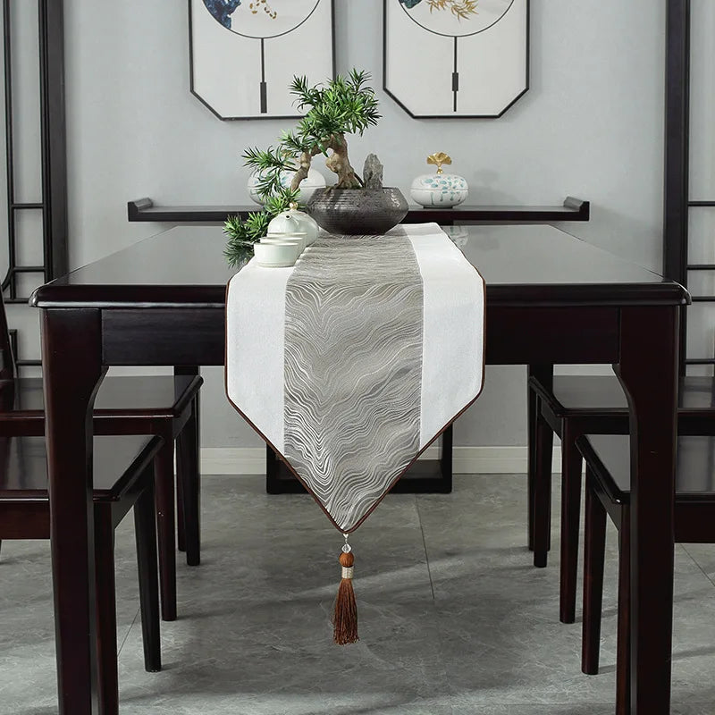 Une élégante table à manger avec un chemin de table orné et des accessoires décoratifs créant une ambiance apaisante et sophistiquée.
