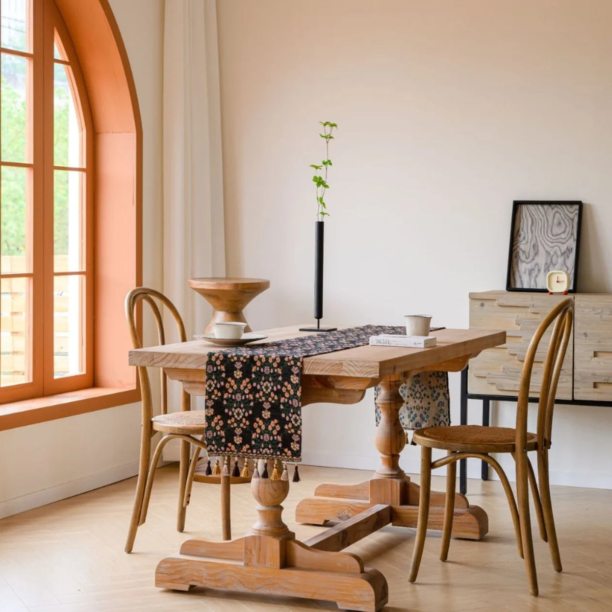 Une salle à manger avec une table en bois et des chaises style vintage, une plante verte et une décoration murale stylée.