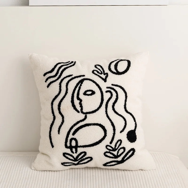 Coussin décoratif blanc et noir avec un motif abstrait de formes géométriques.
