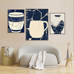 Des motifs abstraits de couleur bleu et blanc sur des toiles encadrées accrochées au mur derrière un canapé blanc.