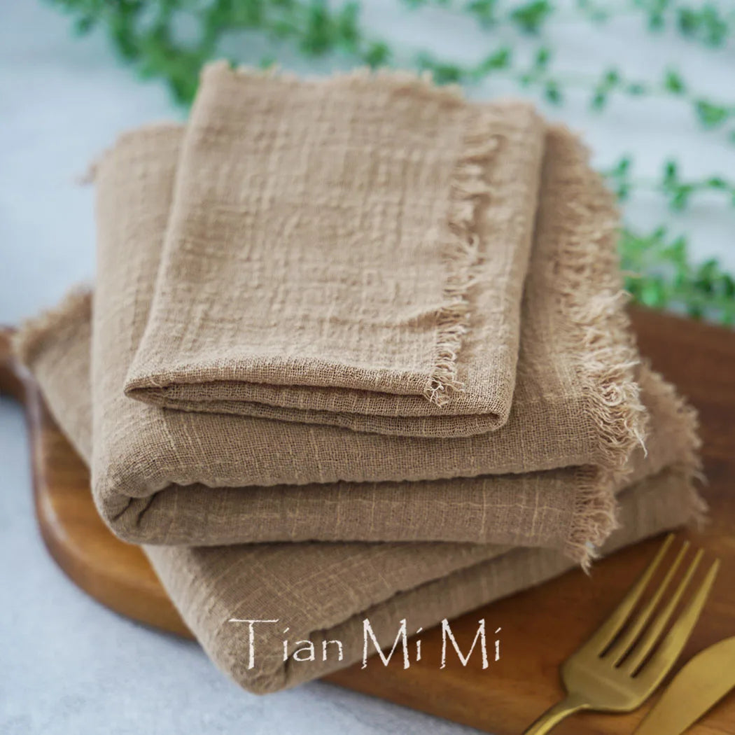 Une pile de serviettes en lin naturel avec un motif fleuri sur un plateau en bois, offrant une présentation élégante et rustique.
