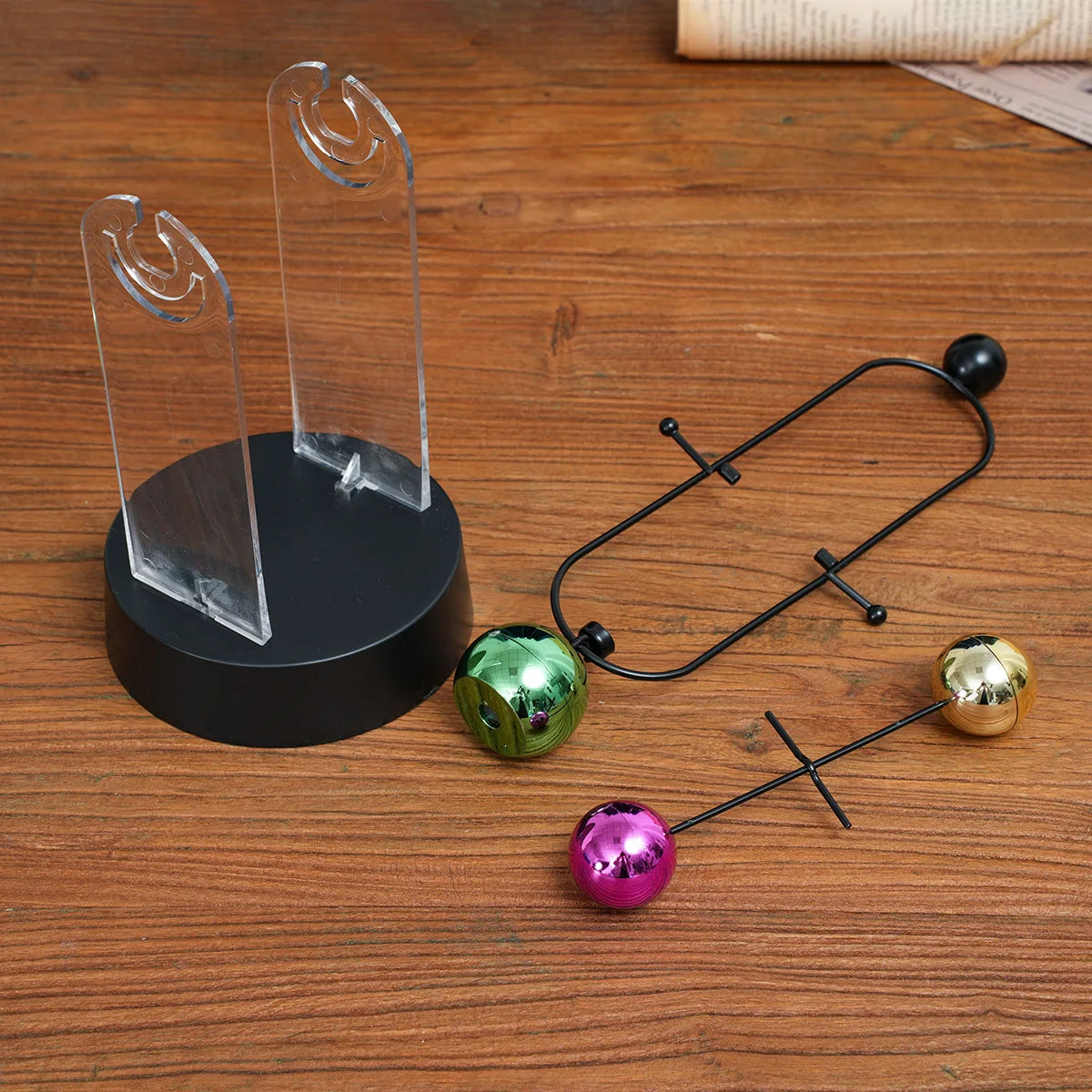 pendule newton sphères colorées structure métallique support transparent base circulaire décoration cinétique moderne