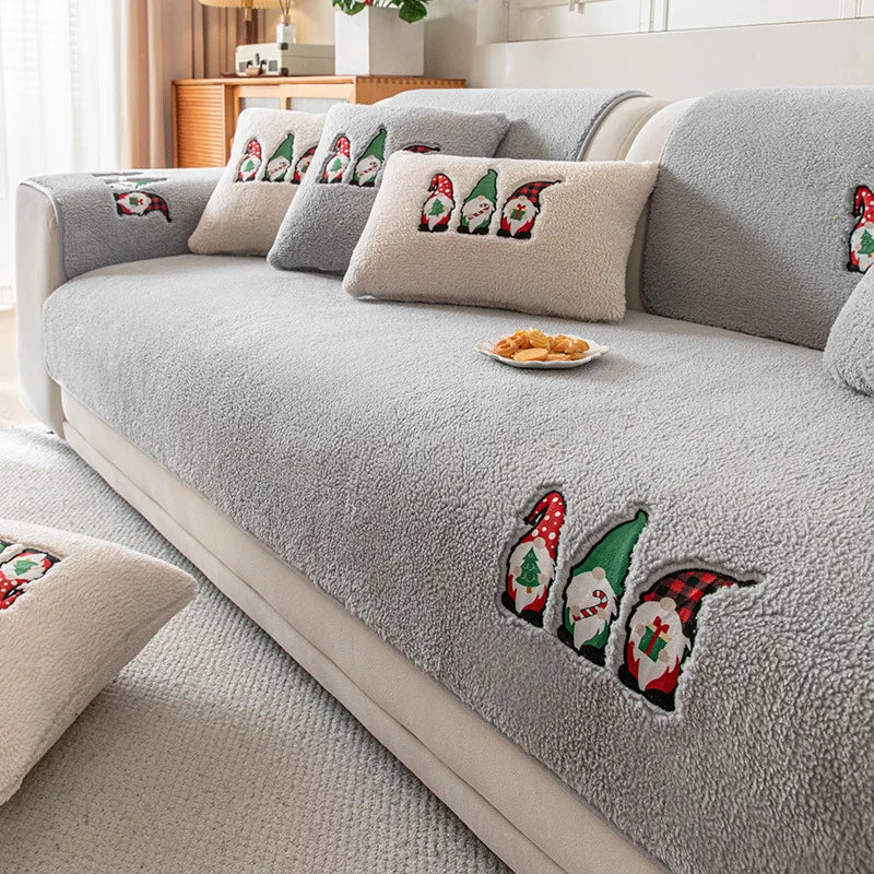 Un canapé gris douillet orné de coussins au motif de petits lutins festifs, une atmosphère confortable et chaleureuse.