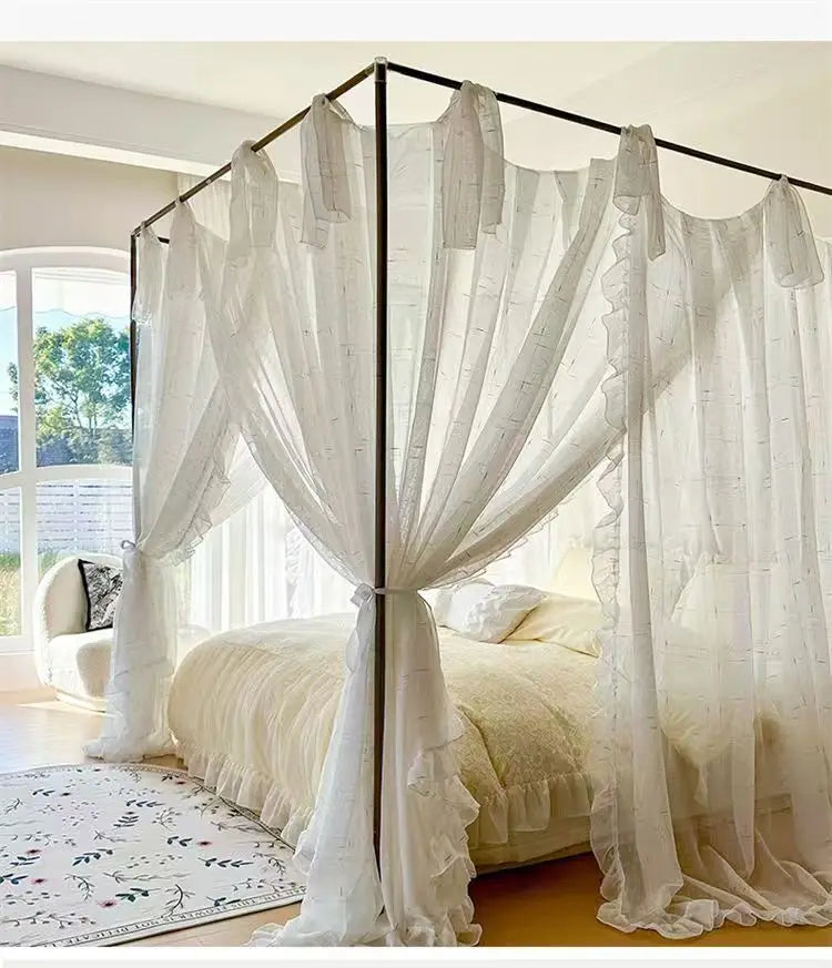 Chambre élégante avec un lit à baldaquin aux rideaux blancs aériens et lumineux, entourant un lit douillet.