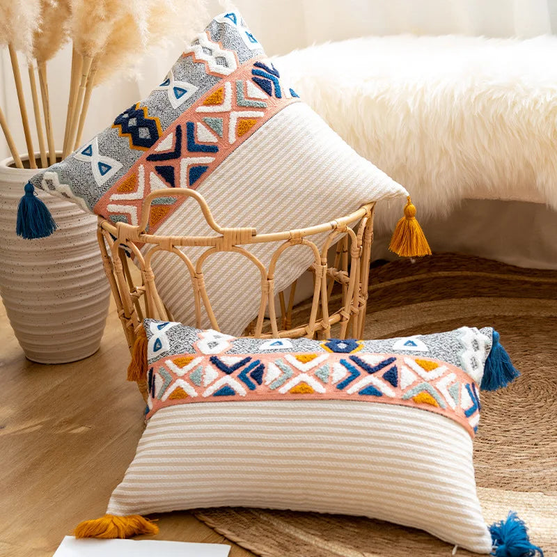 Des coussins colorés sur un canapé en rotin avec des vases sur une table en bois, créant une ambiance chaleureuse et décontractée dans l'espace.