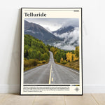 L'image montre une route sinueuse traversant une vallée bordée de montagnes boisées aux couleurs d'automne, avec un texte indiquant le nom de la ville de Telluride.