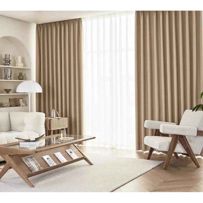 Rideaux élégants pour salon moderne avec fauteuil design, canapé confortable et table basse en bois vitrée, créant une ambiance épurée et chaleureuse. Éclairage naturel optimal grâce aux grandes fenêtres. Idéal pour une décoration intérieure raffinée.