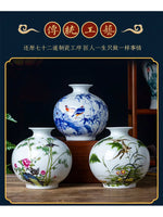 Trois vases en porcelaine peints à la main avec des motifs floraux et animaux traditionnels chinois, sur un meuble en bois foncé.