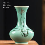 Un vase en porcelaine de couleur vert d'eau avec des motifs floraux peints.