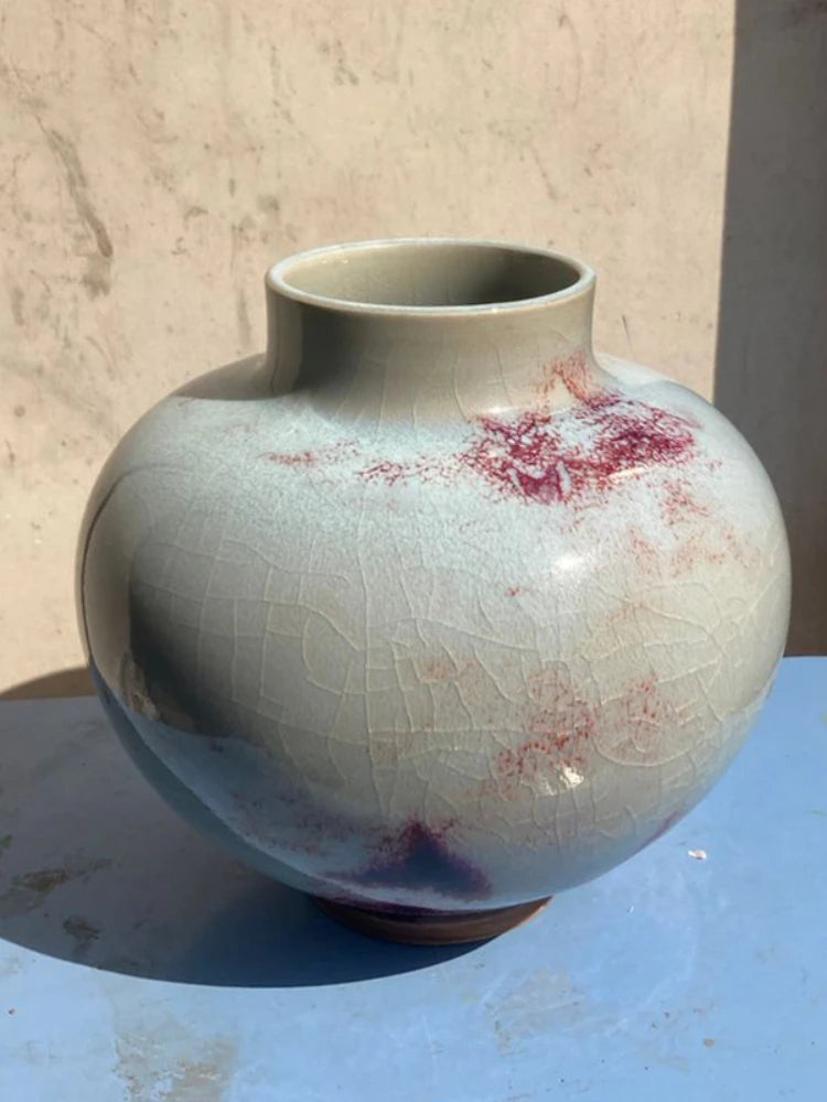 Vase en céramique de style vintage avec un motif abstrait de couleurs douces et une surface craquelée caractéristique.