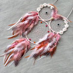 Un magnifique capteur de rêves boho rose et blanc orné de plumes colorées, de perles et de fleurs en dentelle.