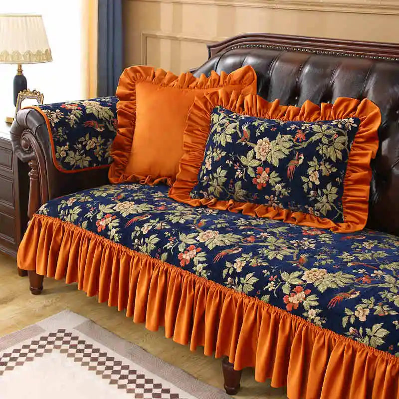 Élégant canapé en cuir brun garni de coussins aux motifs floraux bleu marine et orange, créant une ambiance chaleureuse et raffinée dans cette pièce.