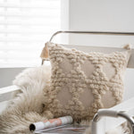 Le coussin moelleux de couleur beige et aux franges décoratives, posé sur un fauteuil argenté, confère une atmosphère cocooning et confortable à cet espace d'intérieur.