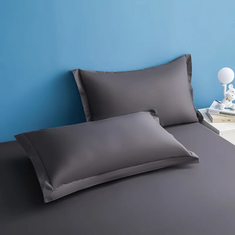 Deux oreillers gris sur une surface blanche, avec un fond bleu clair.