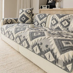 Un canapé douillet et moderne décoré de coussins et d'un motif géométrique gris et blanc, offrant un style bohème et confortable dans la pièce.