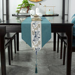 Une élégante chemin de table vert turquoise avec un motif floral bleu et blanc, sur une table en bois sombre avec des décorations asiatiques.