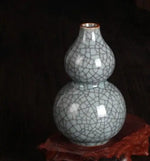Vase en céramique vintage avec un motif de craquelures blanches sur un fond sombre, reposant sur une surface texturée.