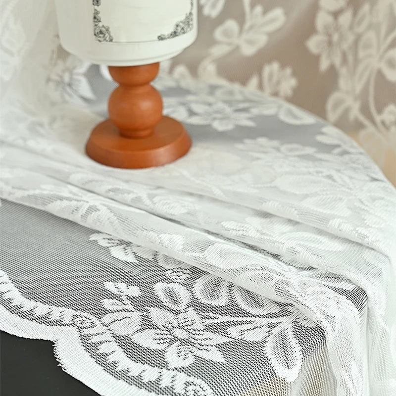 Tissu en dentelle blanche brodée mis en scène sur une table en bois