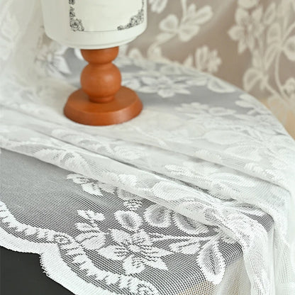 Tissu en dentelle blanche brodée mis en scène sur une table en bois
