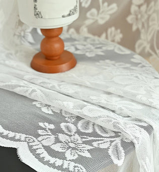 Tissu en dentelle blanche brodée mis en scène sur une table en bois