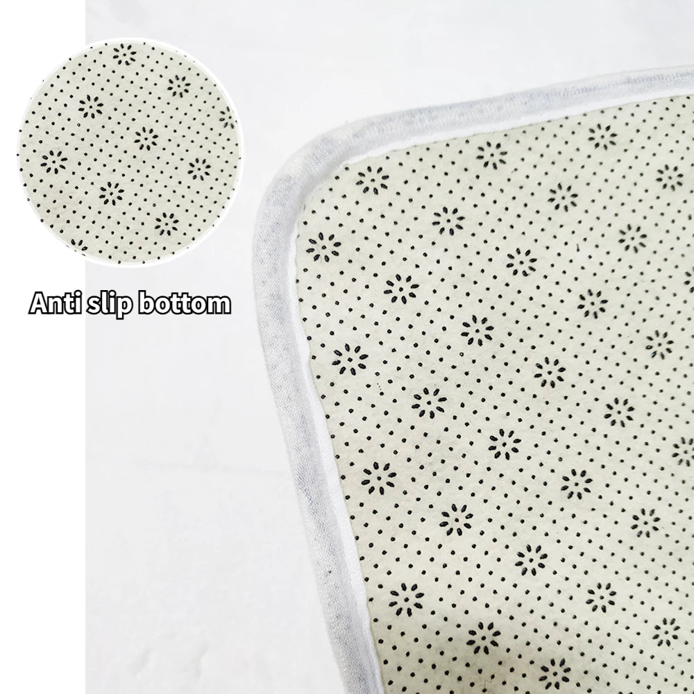 Tapis antidérapant blanc avec motifs de fleurs et de points noirs.