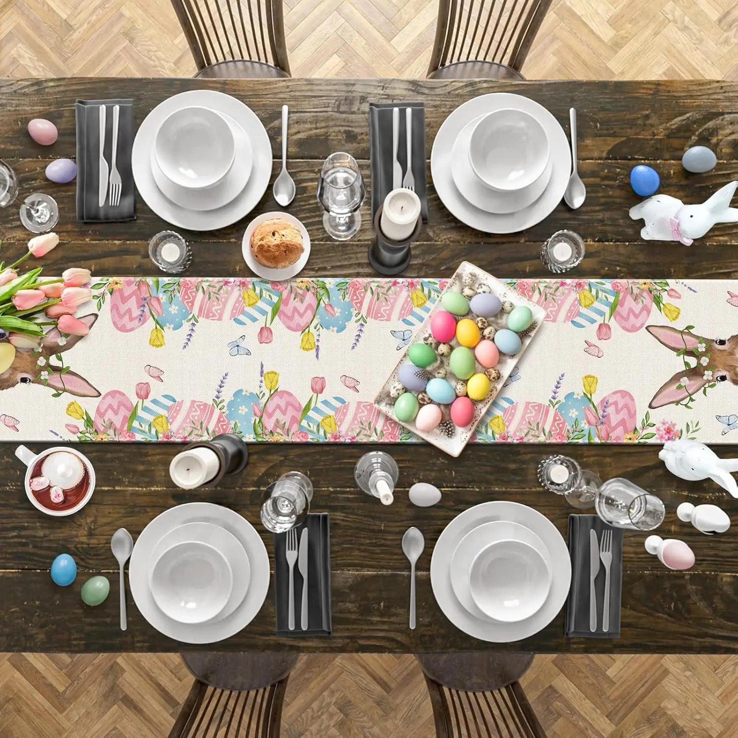 Une belle table de Pâques avec une nappe colorée et des décorations printanières, des assiettes et ustensiles en blanc et noir, et un plat rempli d'oeufs de Pâques multicolores.