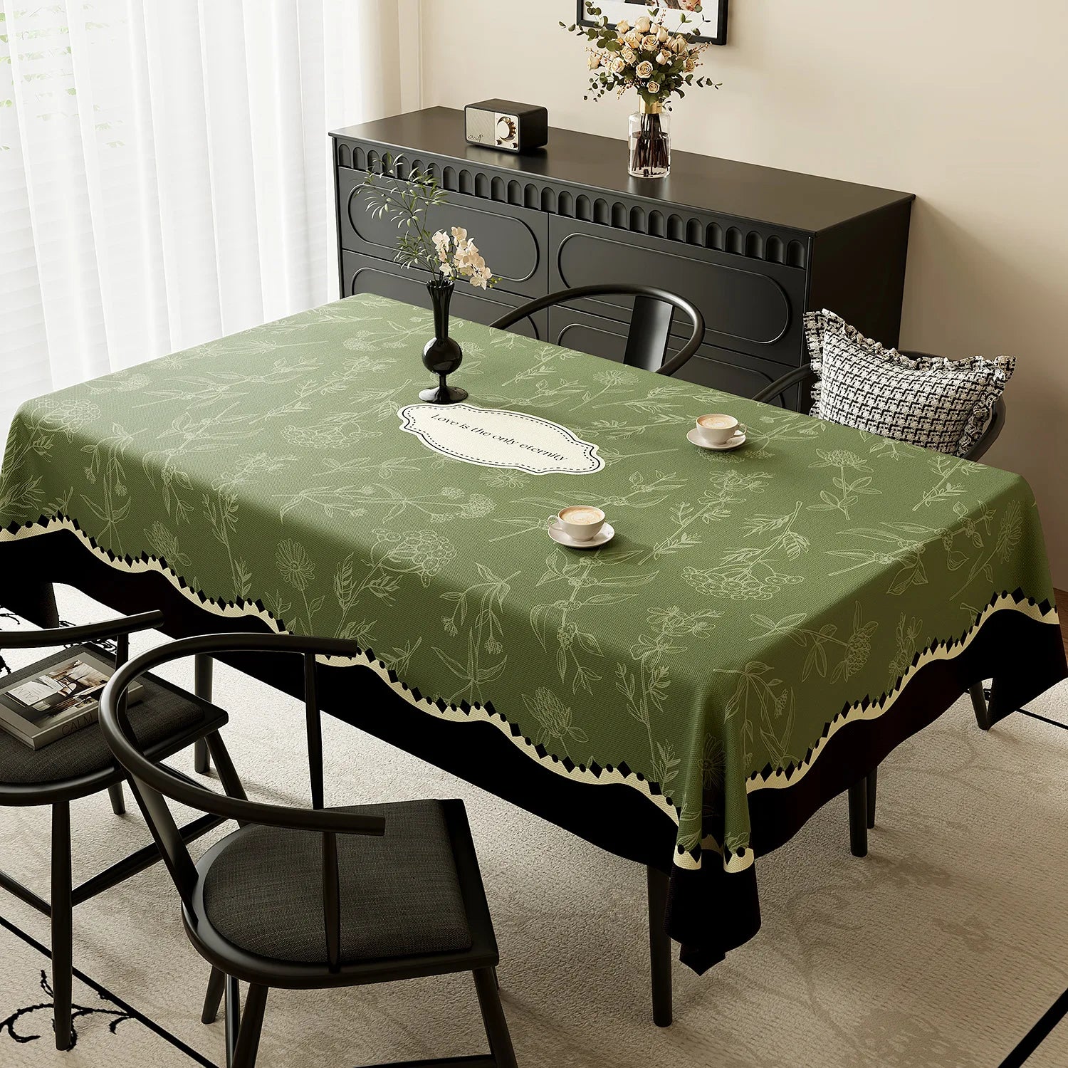 Une nappe de table verte ornée de motifs botaniques délicats, posée sur une table sombre avec des bougeoirs noirs et un bouquet de fleurs, créant une atmosphère élégante et apaisante dans la pièce.