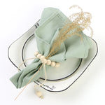 Élégant ensemble de table aux nuances de vert pastel, décoré de tiges dorées et de perles naturelles, reflétant une atmosphère apaisante et raffinée.