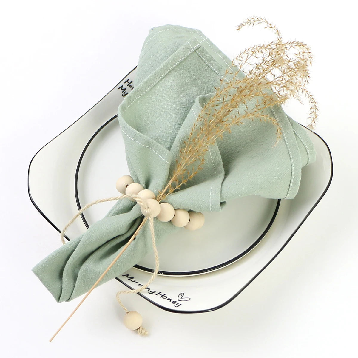 Élégant ensemble de table aux nuances de vert pastel, décoré de tiges dorées et de perles naturelles, reflétant une atmosphère apaisante et raffinée.