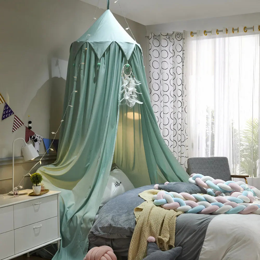 Chambre d'enfant confortable et aménagée avec des couleurs et des textures douces, un lit avec un baldaquin en forme de pyramide et des oreillers multicolores.