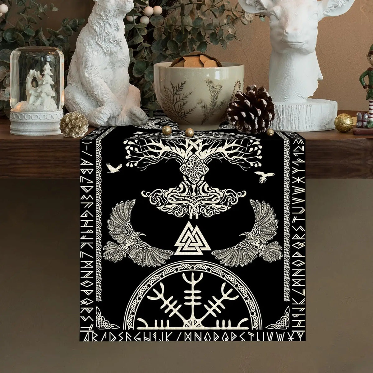 L'image montre une belle décoration murale en noir et blanc, ornée de motifs ethniques et de symboles mystiques, tels qu'un arbre de vie stylisé et des oiseaux. Cet élément décoratif semble s'intégrer harmonieusement dans un intérieur cosy et naturel.