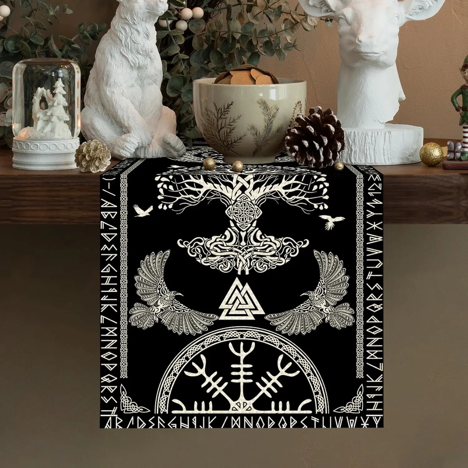 L'image montre une belle décoration murale en noir et blanc, ornée de motifs ethniques et de symboles mystiques, tels qu'un arbre de vie stylisé et des oiseaux. Cet élément décoratif semble s'intégrer harmonieusement dans un intérieur cosy et naturel.