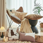 L'image montre un espace de détente confortable avec un fauteuil inclinable, des coussins doux, un plaid et des accessoires décoratifs, créant une ambiance chaleureuse et accueillante.