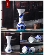 Vase décoratif en porcelaine blanche et bleue avec des motifs floraux, posé sur une étagère en bois dans un intérieur rustique.