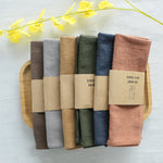 serviettes tissu pliées rustique bohème minimaliste liens anneaux couleurs beige rose vert bleu gris