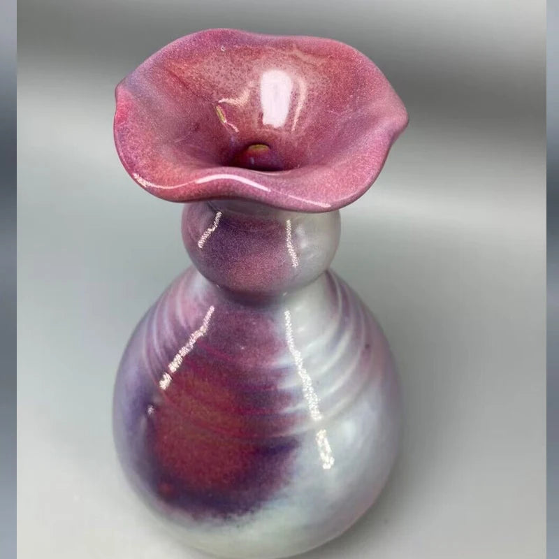 Une fleur en cristal d'un rouge foncé aux pétales délicatement ondulés, posée sur un support transparent.