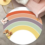 Tapis rond multicolore avec motif arc-en-ciel décorant un espace de vie accueillant avec coussins roses et détails dorés.