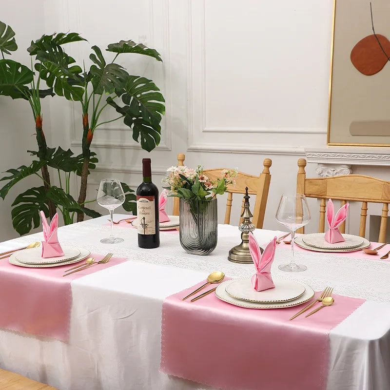 Une table dressée élégamment avec des touches de rose, des verres, des bouteilles de vin et des fleurs, pour un repas chic et raffiné.
