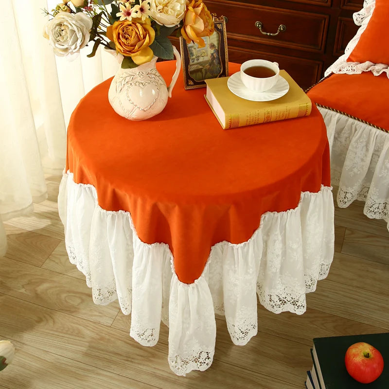 Une table avec une nappe orange et blanche ornée de fleurs et d'accessoires vintage, donnant un air chaleureux et cosy à la pièce.